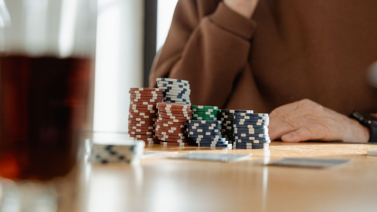 Casual poker scene with colorful poker chips and playing cards on a wooden table.